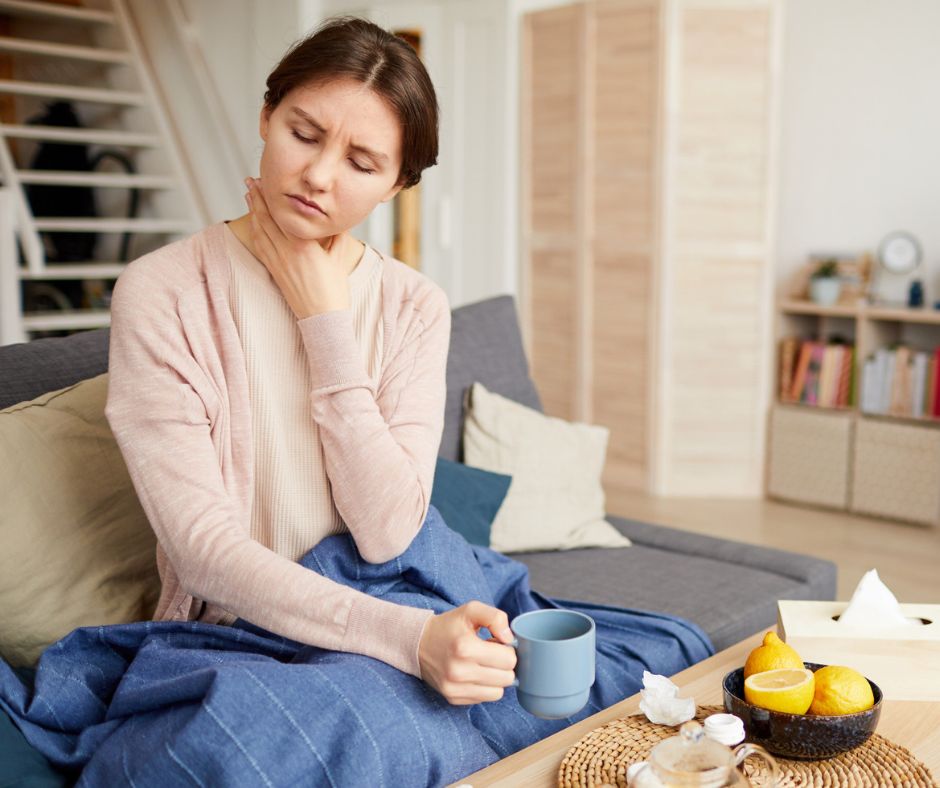 Female having sore throat, holding a cup of tea.